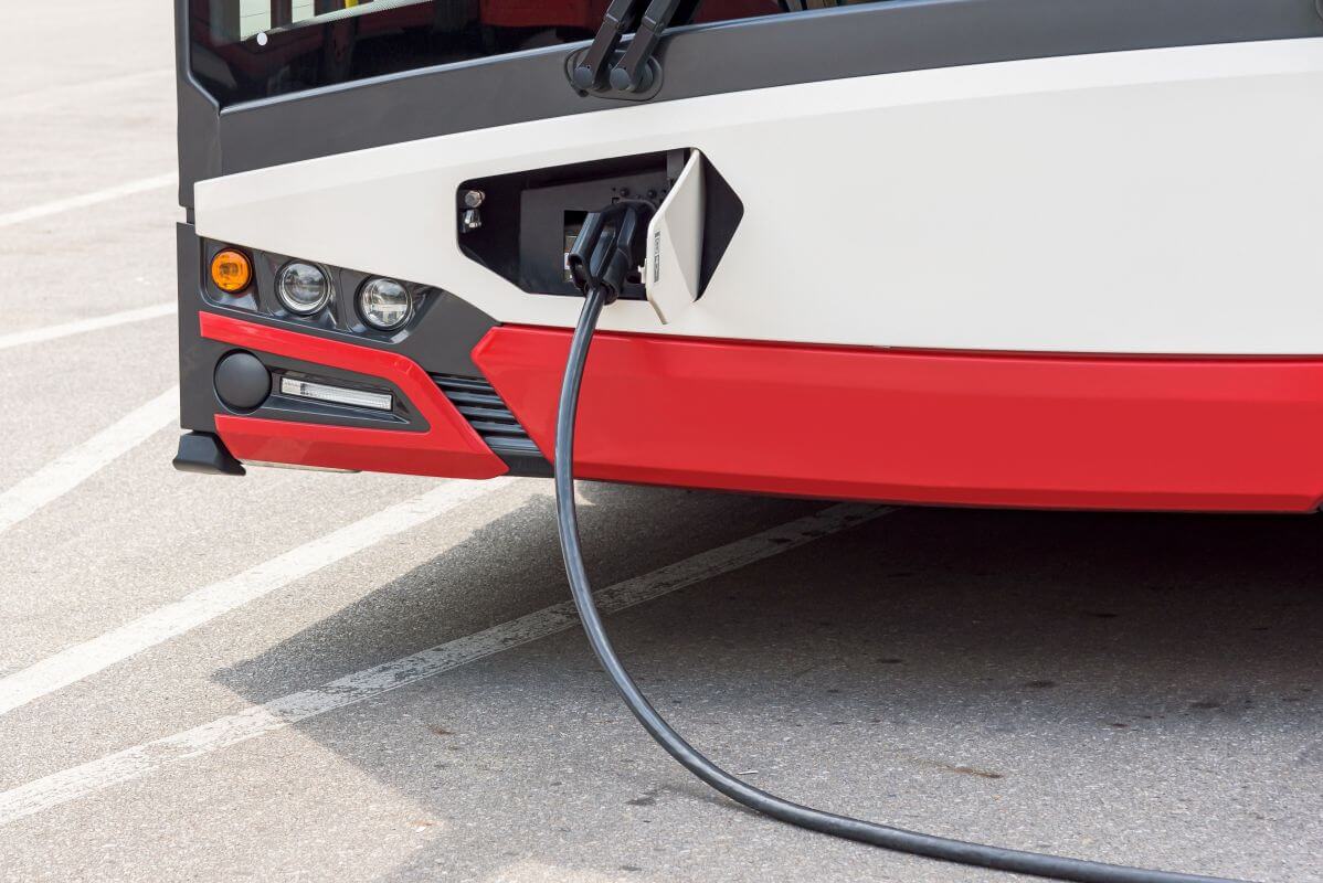 Przedni widok autobusu elektrycznego podłączonego do stacji ładowania autobusów elektrycznych.