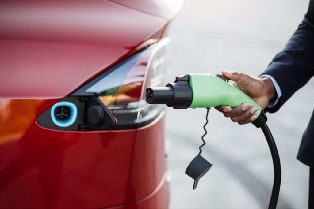 Osoba trzymająca wtyczkę ładowania, zainstalowaną przez producenta stacji ładowania samochodów elektrycznych.