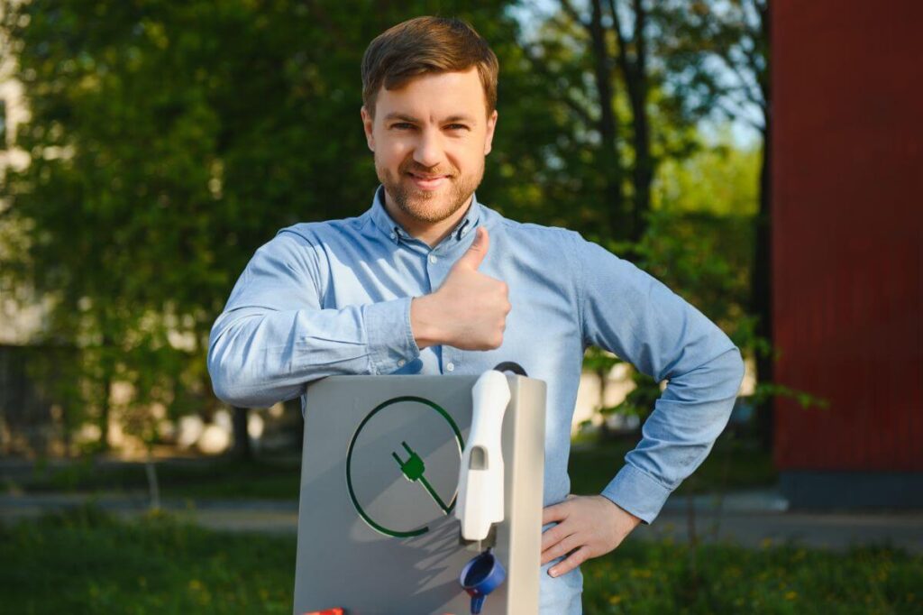 Mężczyzna uśmiechnięty przy montażu stacji ładowania samochodów elektrycznych.